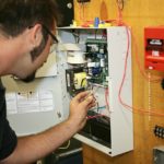 A student electrician wiring a fire alarm system at his technical college.